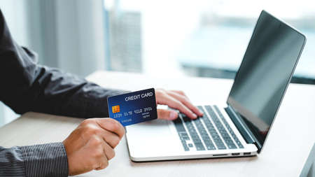 Businessman hand holding credit card to online shopping from home with laptop, payment e-commerce,...