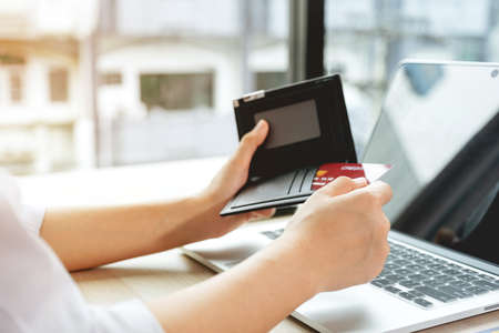 Businesswomen hand take credit cards out of pocket to online shopping on a laptop computer from home for next holidays, payment e-commerce, internet banking, spending money.の写真素材