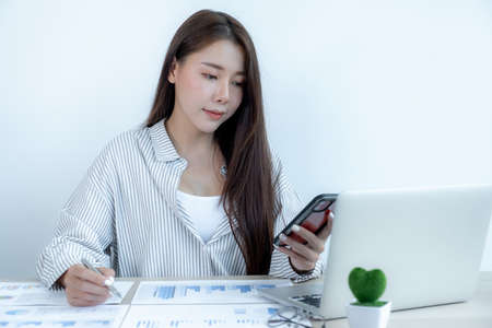 Businesswoman holding pen and analysis the chart with laptop at the office for setting challenging...
