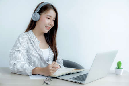 Young woman student taking notes watching laptop study online class video conference education...