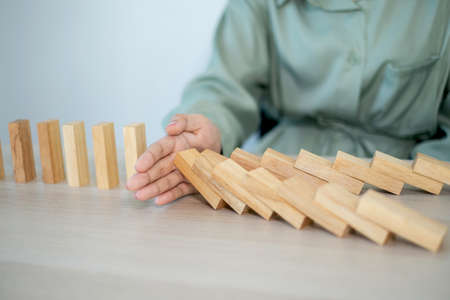 Businesswoman hand stop wooden blocks for protect other wooden block, Concept Risk of management and...