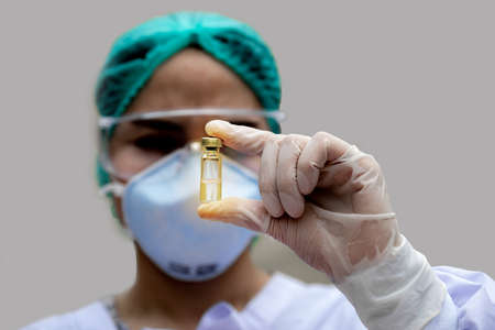 The doctor was wearing a mask, glasses and a hooded robe holding a golden vaccine bottle.