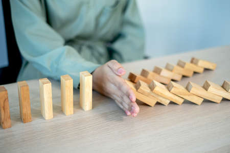 Businesswoman hand stop wooden blocks for protect other wooden block, Concept Risk of management and...