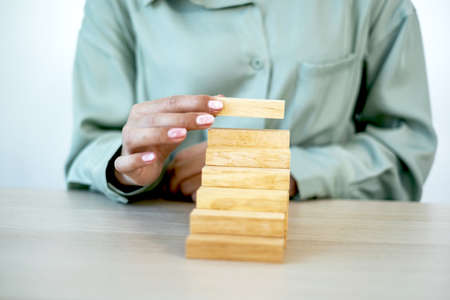 Businesswoman hand holding blocks wood game, Concept Risk of management and strategy plan, growth...
