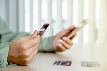 Businesswoman hand holding and use credit card to online shopping from home with smartphone, payment...