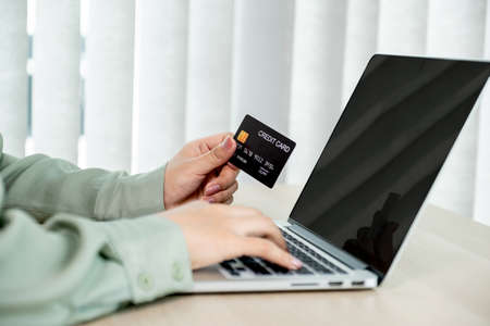 Businesswoman hand holding and use credit card to online shopping from home with laptop, payment...