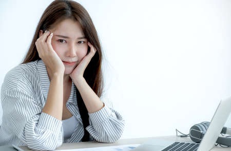 Successful businesswoman sitting in the office working with a laptop, eyes looking at the camera.