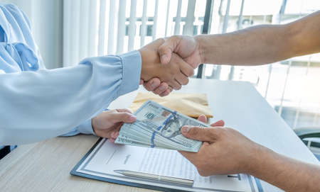 Government officials receiving bribe money from business man in shaking hands the concept of...