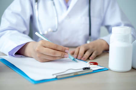 The doctor records the health examination results and medication usage for the patient.の写真素材