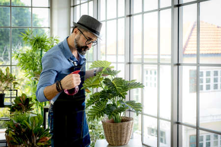 A senior man or grandfather with a mustache enjoys gardening for the tree at home Enjoying hobbies during retirement.の写真素材