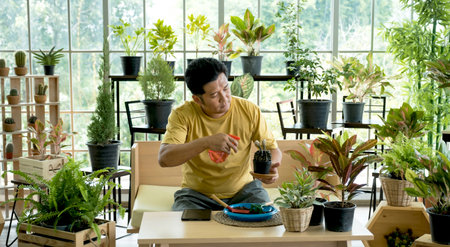 The young man spends his free time caring for the trees in the garden at home as a hobby.の写真素材