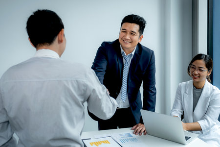 Shaking hands after businesswoman and businessmen team meeting to plan strategies to increase business income. Have a brainstorming graph analysis and discussing for the new target success.の写真素材