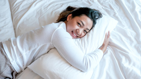 Young Asian woman in plain t-shirts on the luxury white bed.