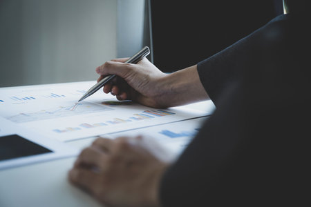 Businesswoman hand holding pen and analysis the chart with laptop at the home office for setting challenging business goals And planning to achieve the new target.の写真素材