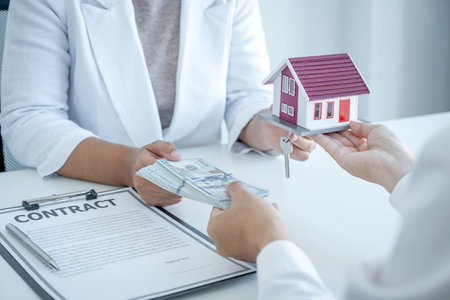 Home Model in hands, The real estate agent explains the business contract, rent, purchase, mortgage, a loan, or home insurance to the business buyer.の写真素材