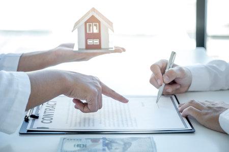 The real estate agent hand pointing and explains the business contract, rent, purchase, mortgage, a loan, or home insurance to the man buyer.の写真素材