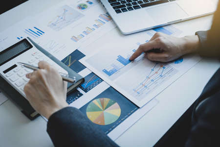 Businesswomen bookkeeper hand pointing to graph use calculator and laptop doing account for paying...