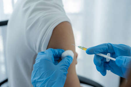 The doctor's hand holding a syringe and was about to vaccinate a patient in the clinic to prevent the spread of the virus.の写真素材