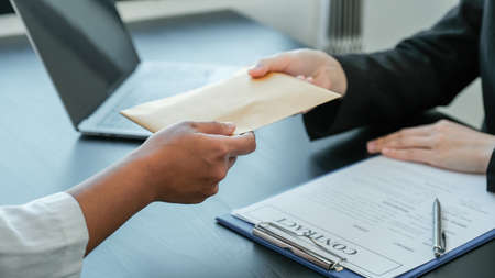 Businessman hand offer bribes money in envelope for signing in a contract of business project,...