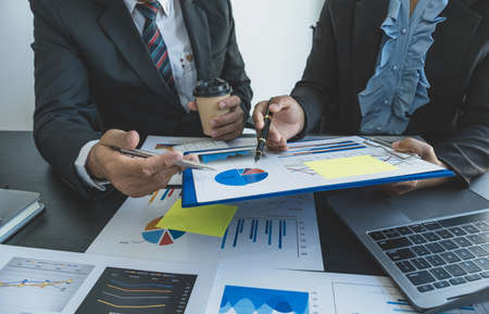 hand holding pen, businesswomen and businessmen team meeting to plan strategies to increase business income. Have a brainstorming finance graph analysis and discussing for the new target success.の写真素材