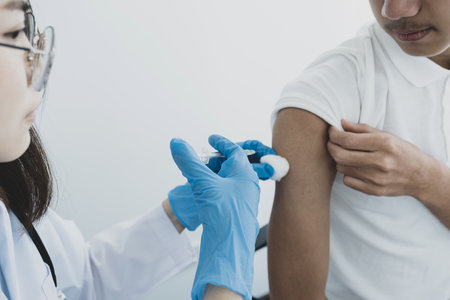 The doctor's hand holding a syringe and was about to vaccinate a patient in the clinic to prevent...
