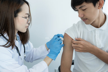 The doctor's holding a syringe and was about to vaccinate a patient in the clinic to prevent the spread of the virus.の写真素材