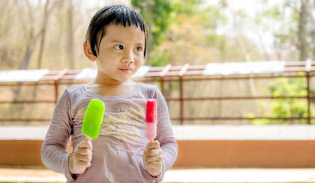 The happy kid girl in a wet shirt eating ice cream   in the natural outdoor background.の写真素材