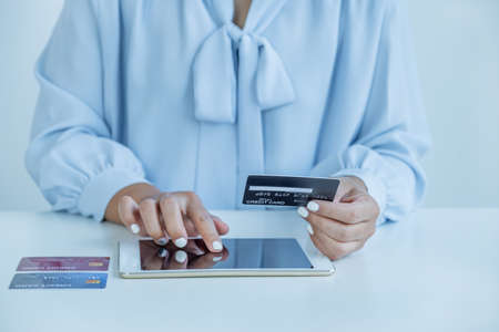 Consumer woman hand holding a mock up credit card, ready to spending pay online finance shopping according to discount products via Tablet from home office.の写真素材