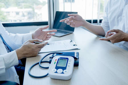 The doctor hand write report and explained examination results to the patient man, healthcare and medical checkup concept.の写真素材