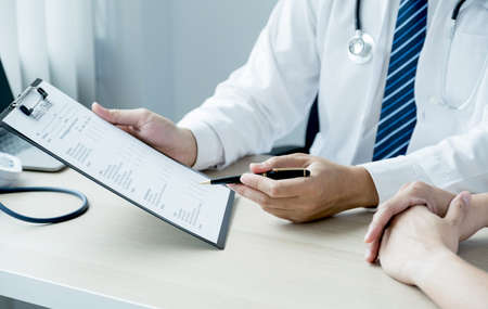 The doctor hand write report and explained examination results to the patient man, healthcare and medical checkup concept.の写真素材