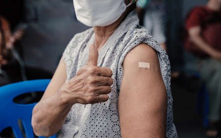 Closeup of senior woman hand showing thumbs up has gone to vaccinate coronavirus covid19 shoulder with bandage at field hospital a place set up by the government,
Healthcare And Inoculation Conceptの写真素材