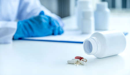 Medicine pill and bottle in front of doctor or pharmacist with a prescription at the pharmacy office, healthcare and medical check-up concept.の写真素材