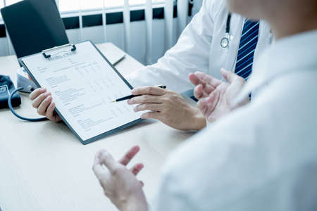 The doctor hand pointing at the report and explained examination results to the patient man,...