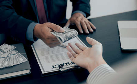 Businessman hand holding dollar bank note money to bribe financial officials or Boss is payout staff salary and anti-bribery.の写真素材