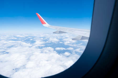 Cloud, blue sky, and Airplane wing has seen through the window of an aircraft view.