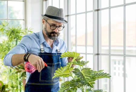 Senior caucasian man or grandfather with a mustache beard enjoys gardening for the tree at home. retirement family lifestyle conceptの写真素材