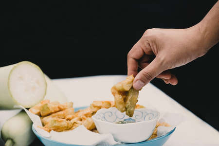Hand picked fried calabash and dipped in seafood sauce on a black background.の写真素材