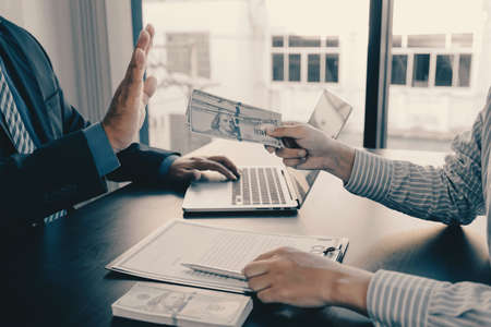 Businessman hand holding dollars note for bribe government officials raise the hand refusing money,...