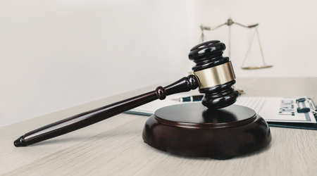 Gavel hammer, justice scale, and contract on the wooden table.