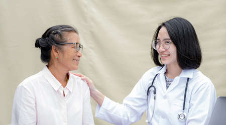 The female doctor supports the patient's shoulder, the elderly and guides friendly health care.の写真素材