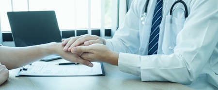 The doctor hands holding patient hand to encourage and explained the health examination results,...