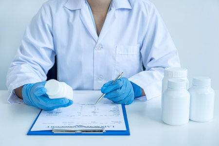 Doctor or nurse hand write a prescription and holding medicine pill bottle at the pharmacy office, healthcare, and medical check-up concept.の写真素材