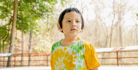 The portrait of happy Asia kid girl in the natural outdoor background.