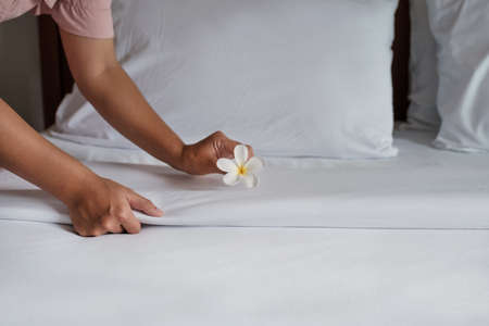 Hands of hotel maid making the bed in the luxury hotel room ready for tourist travel.