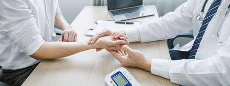 The doctor examines the patient's pulse by hand and records the results, health medical checkup...