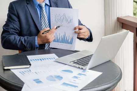 Businessman hand holding pen, analysis the graph with laptop at the home office for setting challenging business goals And planning to achieve the new target.の写真素材