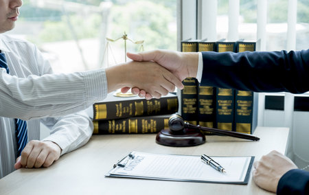 Handshake after Lawyer  providing legal consult business dispute service to the man at the office with justice scale and gavel hammer.の写真素材