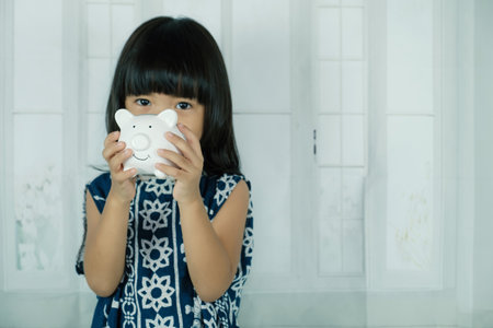 White piggy bank in Asian little girl hand, learn to saving for the future concept.の写真素材