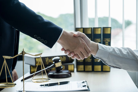 Handshake after Lawyer  providing legal consult business dispute service to the man at the office with justice scale and gavel hammer.の写真素材