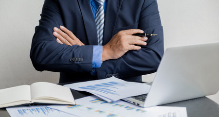 Businessman hand holding pen, analysis the graph with laptop at the home office for setting challenging business goals And planning to achieve the new target.の写真素材